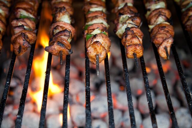 Grilled chicken skewers served over lemony couscous, gathered around a summer outdoor table with family and friends