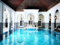 Experience Authentic Moroccan Villa Hammam: A Guide for Maghrebi Diaspora Travelers Maghrebi woman relaxing in a traditional Moroccan Villa Hammam with lush gardens and ancient architecture in the background