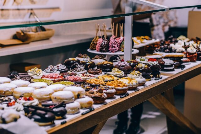 A woman enjoying halal pastries at a vibrant pastry shop in Singapore, surrounded by various dessert options