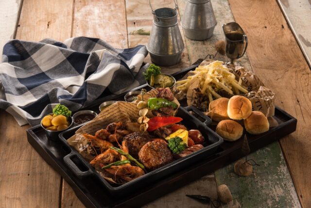 Family enjoying Bahraini fusion dish at a vibrant outdoor restaurant