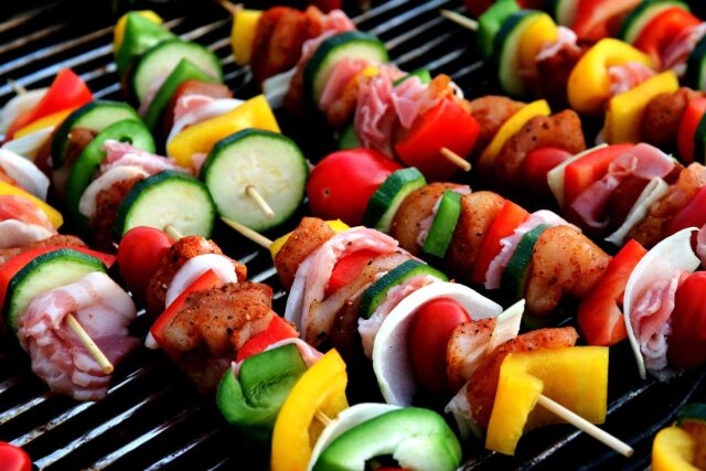 Lemon Chicken Skewers and Couscous Feast Lemony chicken skewers served on a plate with Maghrebin-style couscous, a colorful table setting, and a group of people enjoy