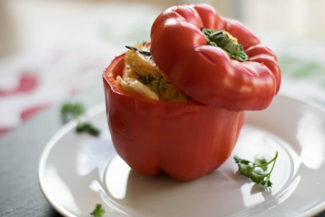 Spiced couscous filling stuffed inside colorful bell peppers on a wooden platter