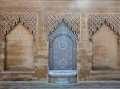 Discovering Morocco’s Rich Judeo-Amazigh Cultural Heritage: A Journey Through Time Woman wearing traditional Amazigh attire amidst Moroccan marketplace with Jewish artifacts