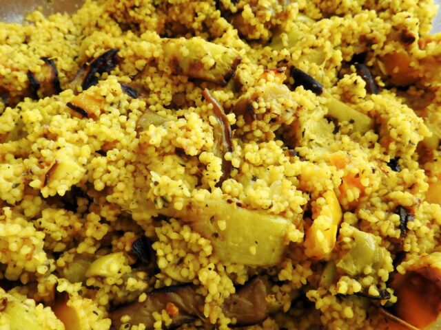 North African Couscous Salad Preparation Woman preparing North African Couscous Salad with colorful vegetables and herbs on a rustic wooden table
