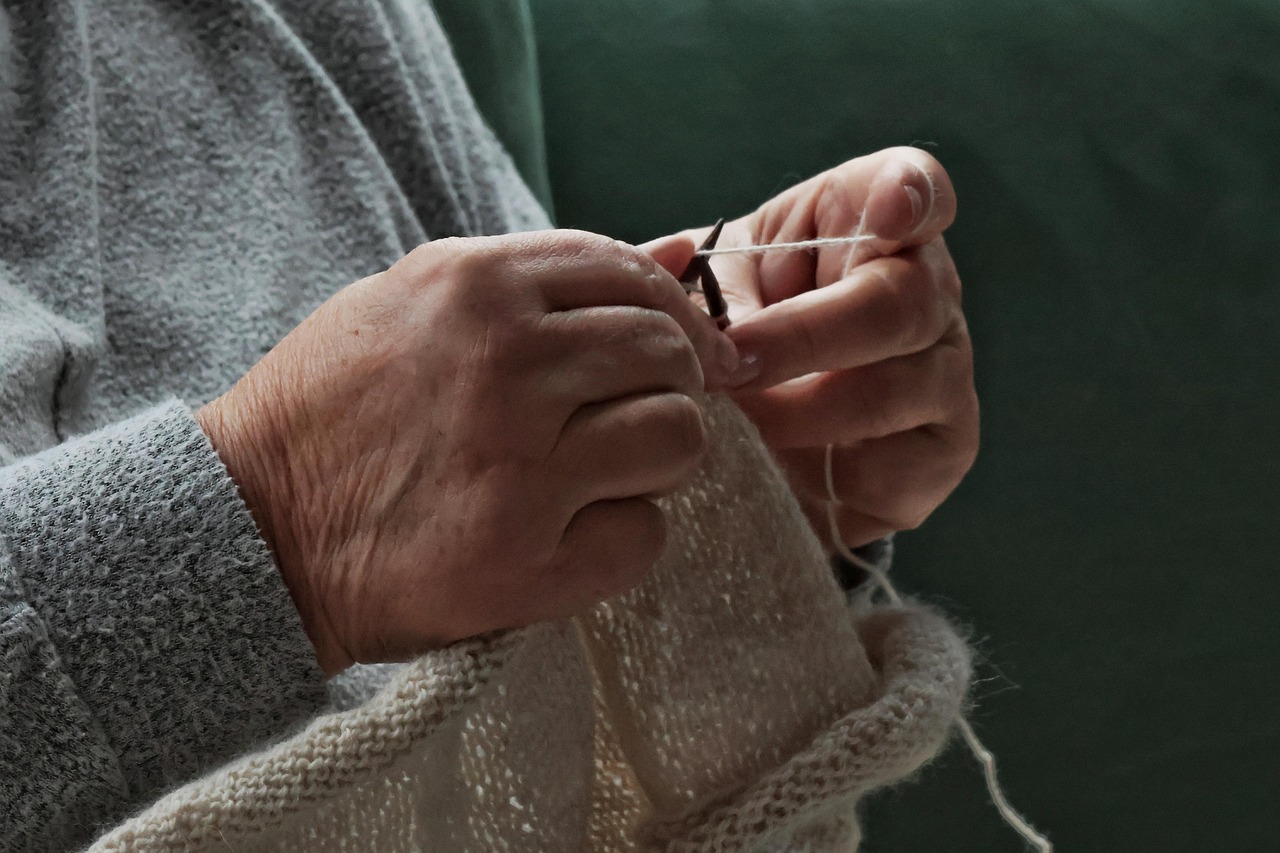 Woman wearing traditional Amazigh jewelry, working on a hand-woven carpet in a Moroccan market